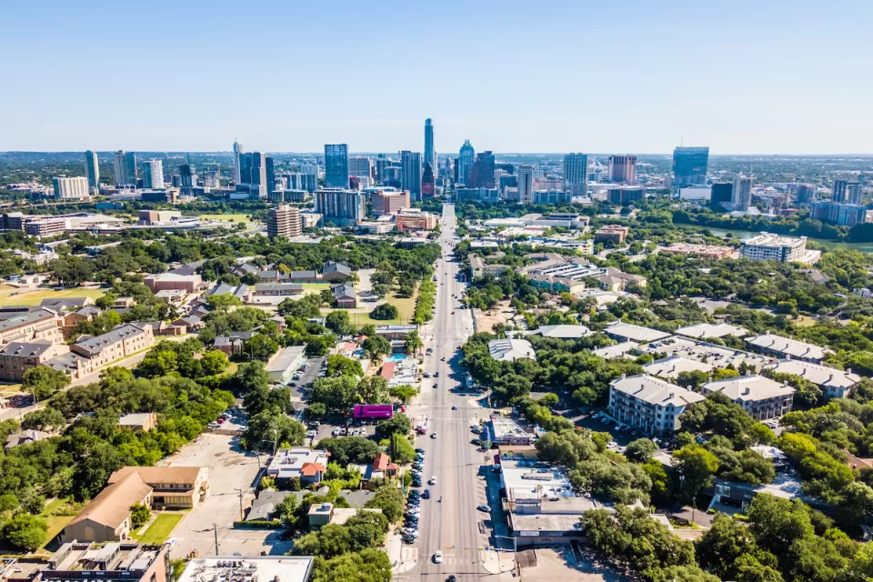 Aerial view of downtown Austin, Texas with state capitol dome at end of long, straight boulevard.